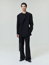 model wearing relaxed tailored black double weave wool crewneck jacket with long belt and matching wide-leg pants
