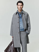 model wearing gray mouline wool relaxed trench coat over blue denim jacket holding brown leather bag