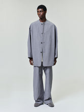 Front view of man wearing oversized gray buttoned jacket and matching wide-leg pants with gray shoes