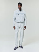 male model wearing bleach washed denim straight leg five-pocket jeans with matching jacket and gray boots