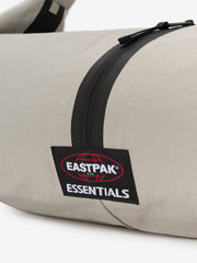 Essentials Shell Bag close up in light beige with a black curved zipper and Eastpak Essentials woven label against a clean white background