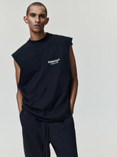 Essentials FW26 Classic Cut-Off black sleeveless top with raw cut armholes worn by a model with dark drawstring trousers in a studio Tops product view