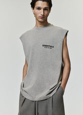 Essentials FW26 Classic Cut-Off gray sleeveless top with raw armholes and Fear of God logo worn by a model with tailored gray trousers in a studio Tops view