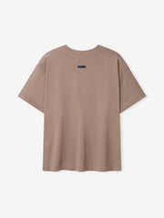 Back view of a plain short-sleeve t-shirt in muted sandy beige with a small black label near the neckline
