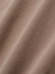 Close-up of soft, smooth fabric in a muted warm beige tone with subtle texture details visible