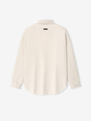 Back view of a natural-colored long-sleeve shirt with buttoned cuffs and a small black label near the collar