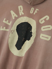 Close-up of dune pearl Liberation Now Hoodie showing textured black profile graphic with faded off-white "FEAR OF GOD" text FGDSYF-FLC004U gallery 0