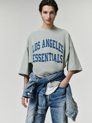 Rams Merch Tee gray oversized short sleeve T shirt with bold blue Los Angeles Essentials lettering styled on a model in a casual Tops look