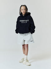 Kids FW26 Classic Sweatshort in light gray with elastic waistband and side pockets styled on a child with a black Essentials Fear of God hoodie and sneakers Bottoms