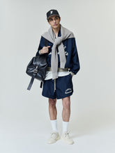 Yankees Gym Short in navy blue featuring a relaxed fit with white printed "Yankees Essentials" text on soft fabric, styled casually with a matching jacket, cap, and sneakers.