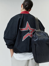 Person wearing Astros Half Zip Pullover with a large red and white star design on the back, paired with light pants and carrying a textured black bag over one shoulder.