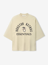 Cream-colored oversized short-sleeve top featuring black "Houston Astros Essentials" text and a vintage-style eagle graphic, part of the Astros Al Merch Tee collection.