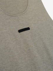 Essential Tank in a muted light gray heather fabric featuring a rounded neckline and a small black rectangular logo patch centered on the chest for a subtle, casual top.