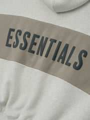 Cropped Relaxed Panelled Hoodie with a soft vanilla heather base and a wide muted taupe panel across the chest featuring raised black ESSENTIALS lettering for a modern streetwear look.