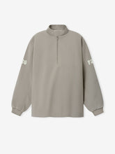 Half Zip Track Jacket in a muted taupe shade featuring a relaxed fit, long sleeves with subtle white printed lettering on each arm, and a front half-zip closure for versatile outerwear.