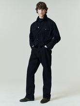 Model wearing a black denim jacket paired with Denim 5-Pocket Jeans in a matching deep black wash, styled with dark suede shoes for a sleek, minimal look.