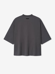 Merch Tee in dark grey featuring an oversized relaxed fit with dropped shoulders and a small black rectangular detail near the neckline for a minimalist casual top.