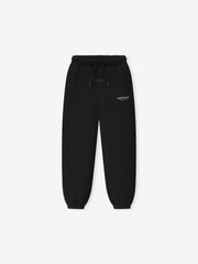 Kids Essentials FW26 Classic Sweatpant in black displayed flat with elastic drawstring waistband tapered legs ribbed cuffs and subtle Fear of God Essentials logo Bottoms