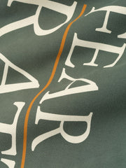 Close-up of dark green FAMU Lounge Sweatpant fabric with white text and a thin orange vertical stripe, file X1Yu9LnA.jpg