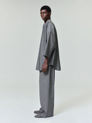 side profile of model wearing relaxed fit grey cotton-wool mandarin collar shirt with cropped sleeves and matching wide-leg trousers