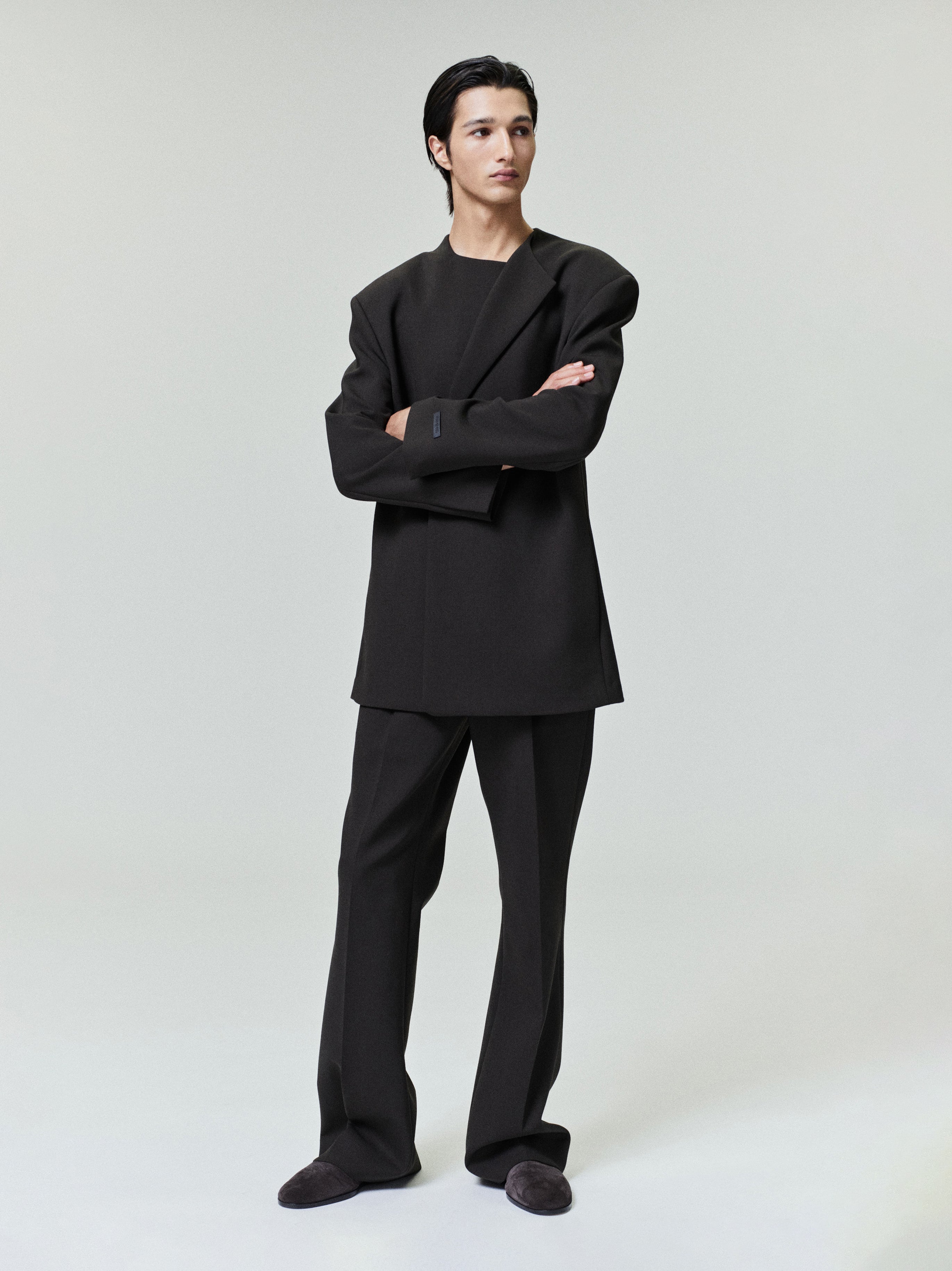 male model in black double-weave virgin wool tailored high-waisted flared pants with matching structured jacket