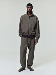 man wearing olive bonded nylon tech track jacket and matching pants with elasticated cuffs and collar