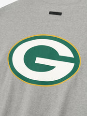 Close-up of concrete heather Packers 90s 3/4 Sleeve Football Tee showing large green and white G logo with gold outline centered