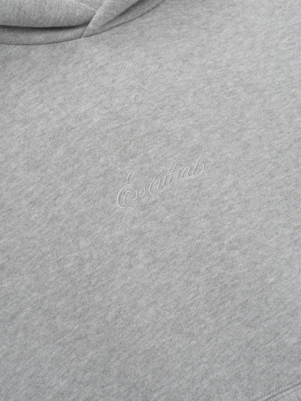 Close-up of a gray hoodie with essentials embroidery script