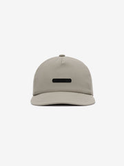 5 Panel Nylon Hat in muted beige featuring a sleek, minimal design with a small black rectangular logo plaque centered on the front panel for casual, versatile headwear.