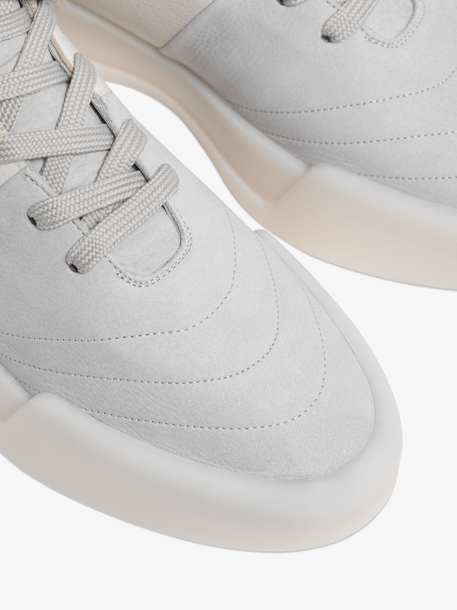 close-up of light grey high-top basketball sneakers with smooth matte leather and thick translucent rubber sole edges