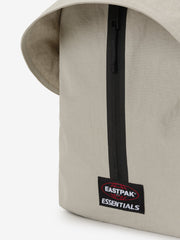Essentials Backpack in beige close up showing a black vertical zipper and Eastpak Essentials logo patch on smooth fabric with a curved top edge