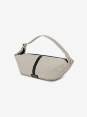 Essentials Shell Bag in light beige with a curved shoulder strap black zip detail and small woven label displayed against a clean white background