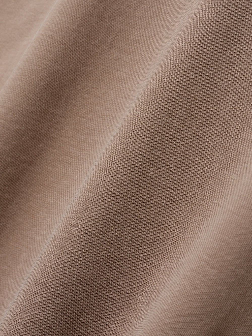 Close-up of soft, smooth fabric in a muted warm beige tone with subtle texture details visible