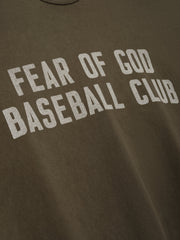 Close-up of faded brown fabric with large distressed white "FEAR OF GOD BASEBALL CLUB" text printed across front