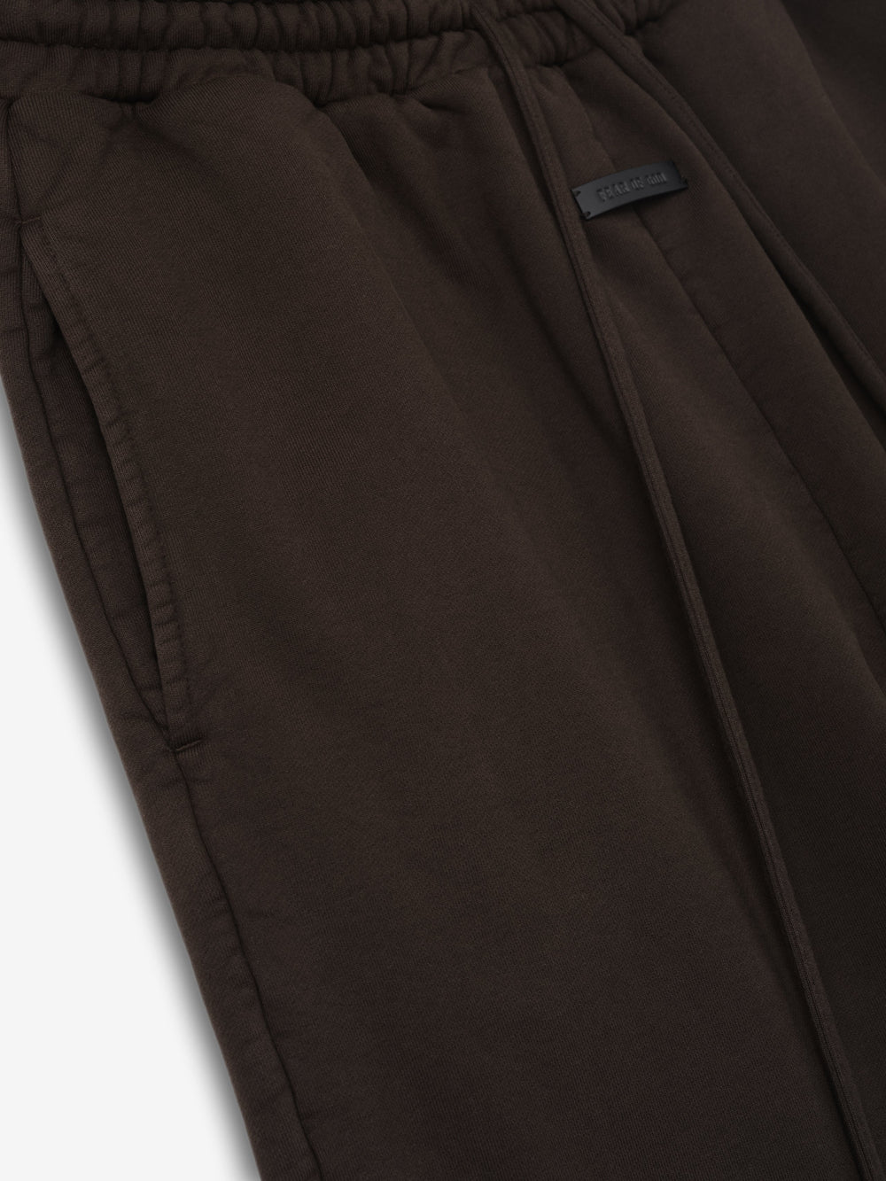 Dark brown sweatpants with elastic waistband, front drawstring, side pockets, and a small rectangular patch detail