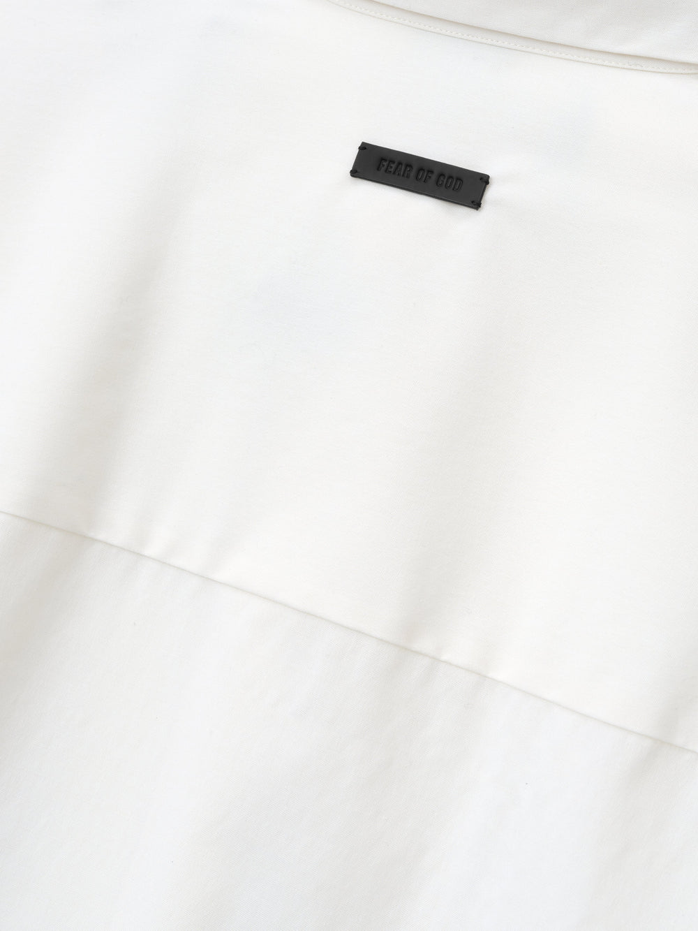 close-up detail of white cotton wool oxford shirt showing black Fear of God label stitched above horizontal seam