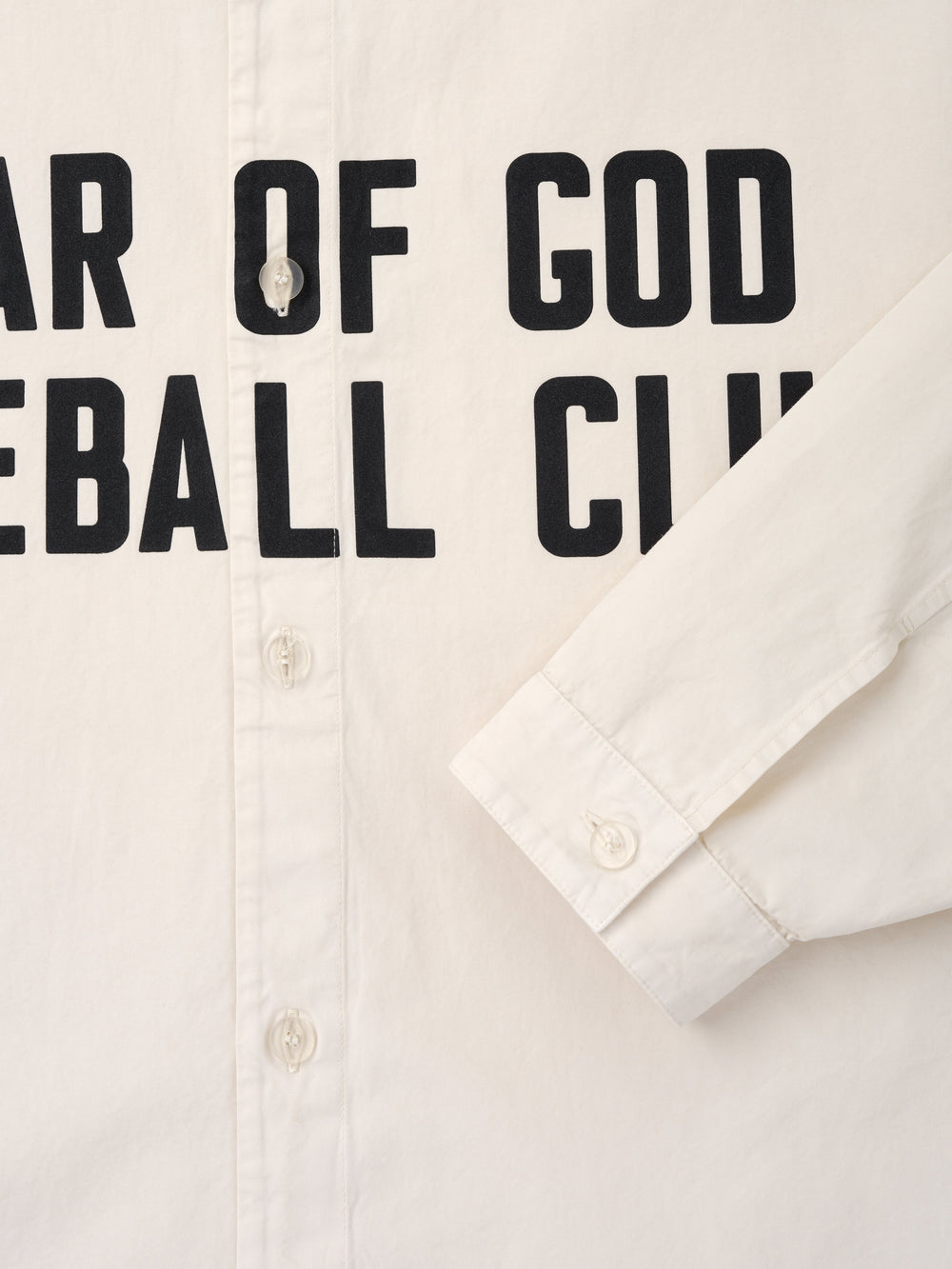 Close-up of natural off-white shirt front with visible buttons and black bold text partially reading "Baseball Club
