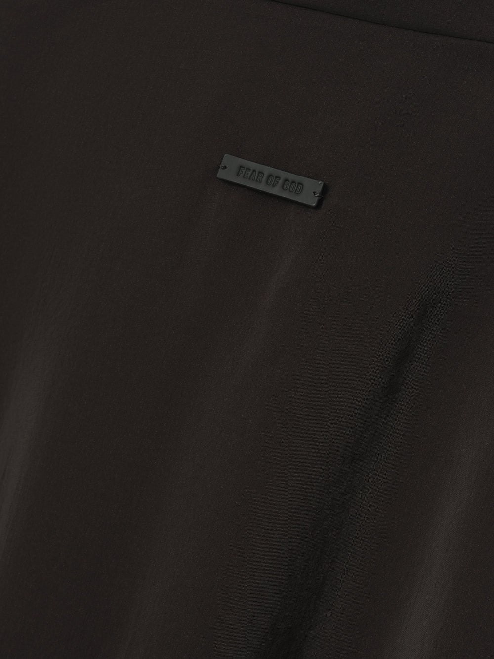 close-up of black technical crinkle viscose fabric with small Fear of God branded rubber tag detail