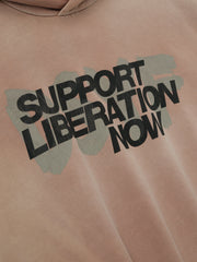 Close-up of dune pearl Liberation Now Hoodie with bold black "Support Liberation Now" text over distressed gray brushstroke, gallery 0