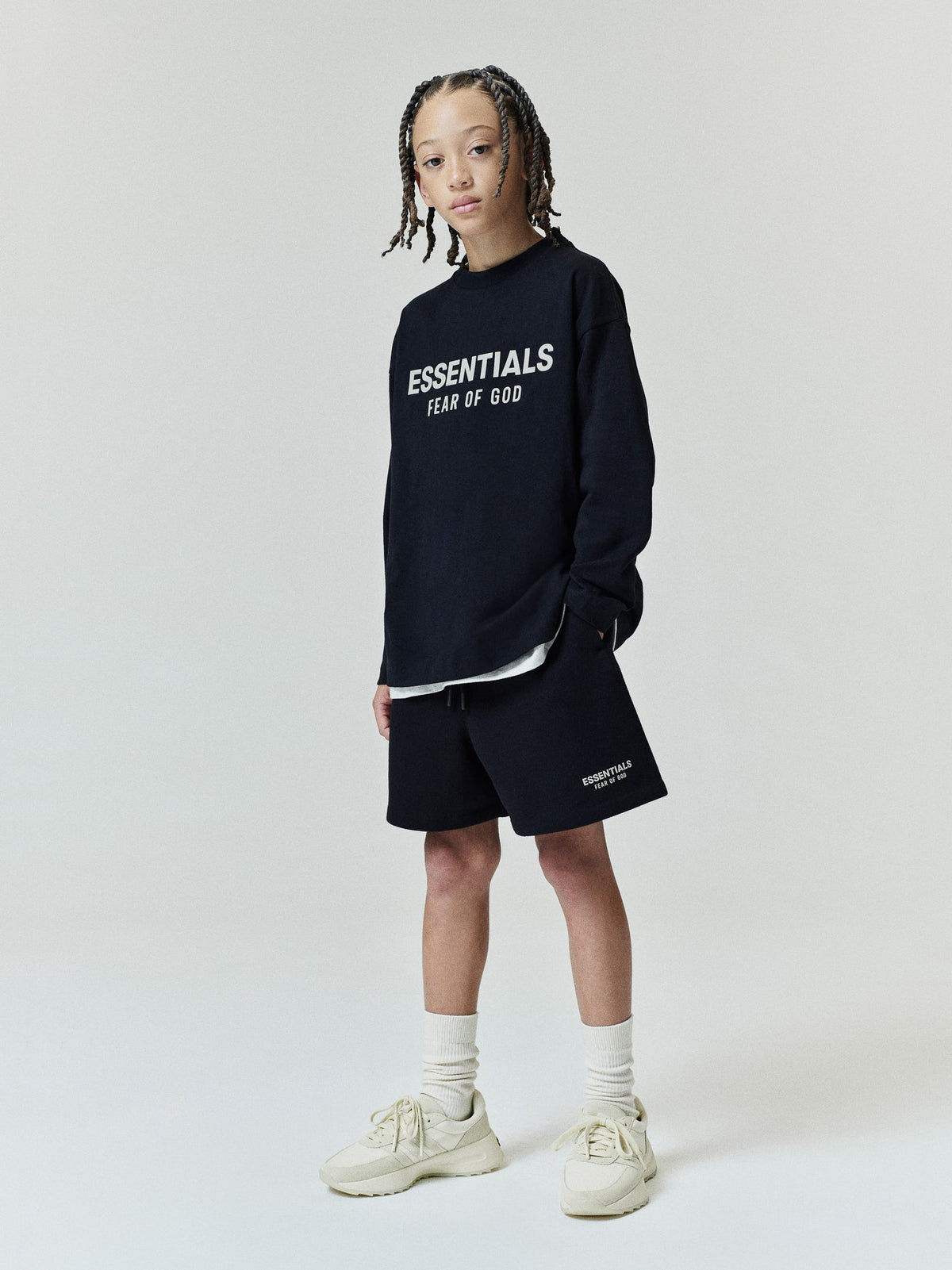 Kids FW26 Classic Sweatshort in black with elastic waistband and relaxed fit styled on a child with an Essentials Fear of God sweatshirt and sneakers Bottoms