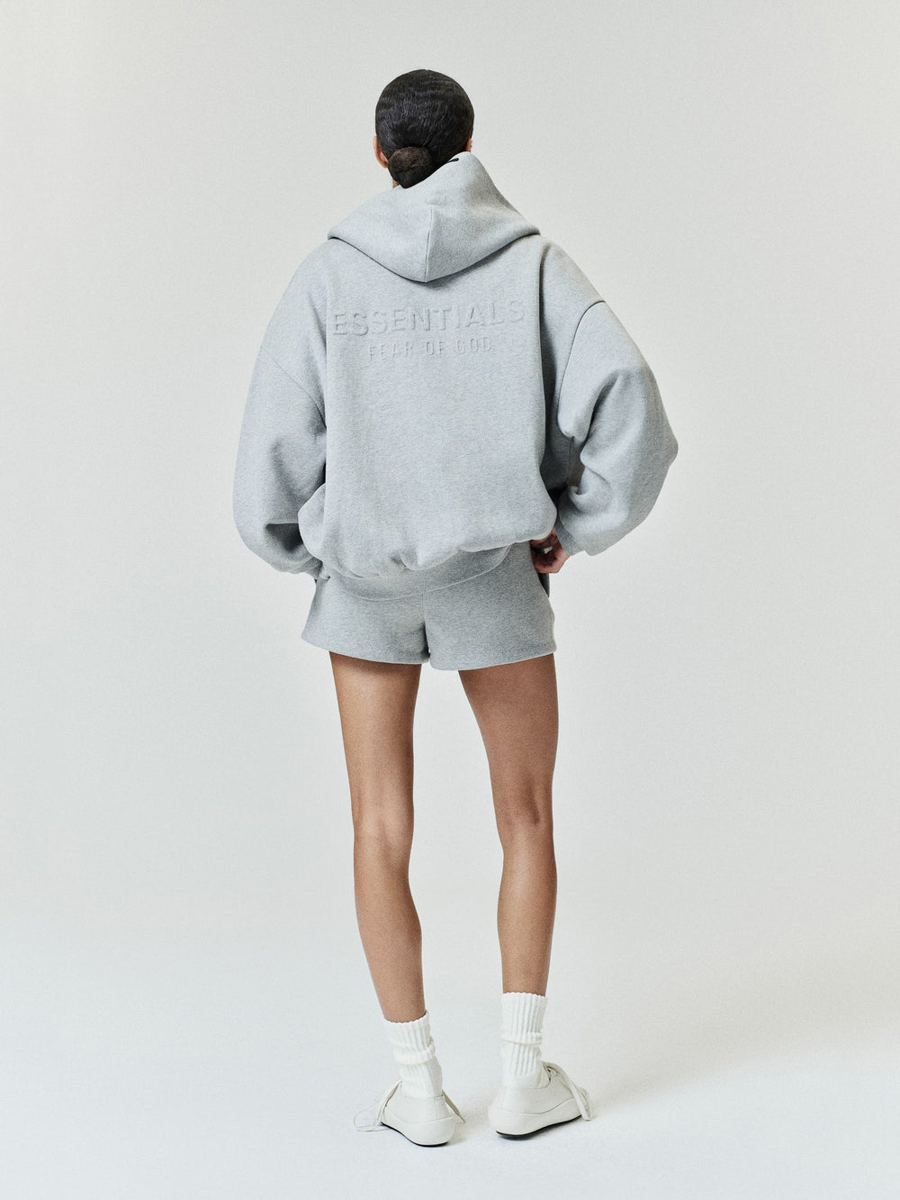 Womens Embossed FW26 Cropped Zip-Up Hoodie in light gray shown from the back with hood embossed lettering ribbed hem and relaxed sleeves Tops