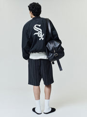 Model wearing White Sox Half Zip Pullover in black with a large white team logo on the back, styled with pinstriped shorts, white socks, black slides, and a black leather backpack.