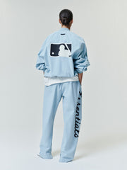 Back view of a model wearing a light blue Mlb Full Zip Bomber paired with matching pants featuring bold script down one leg, styled with a relaxed fit and crisp, clean lines.