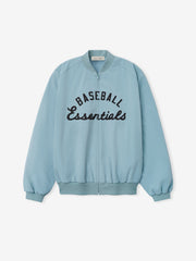 MLB Full Zip Bomber in soft stone blue featuring a full front zipper, ribbed collar, cuffs, and hem, with bold black embroidered "Baseball Essentials" text across the chest, designed as lightweight outerwear.
