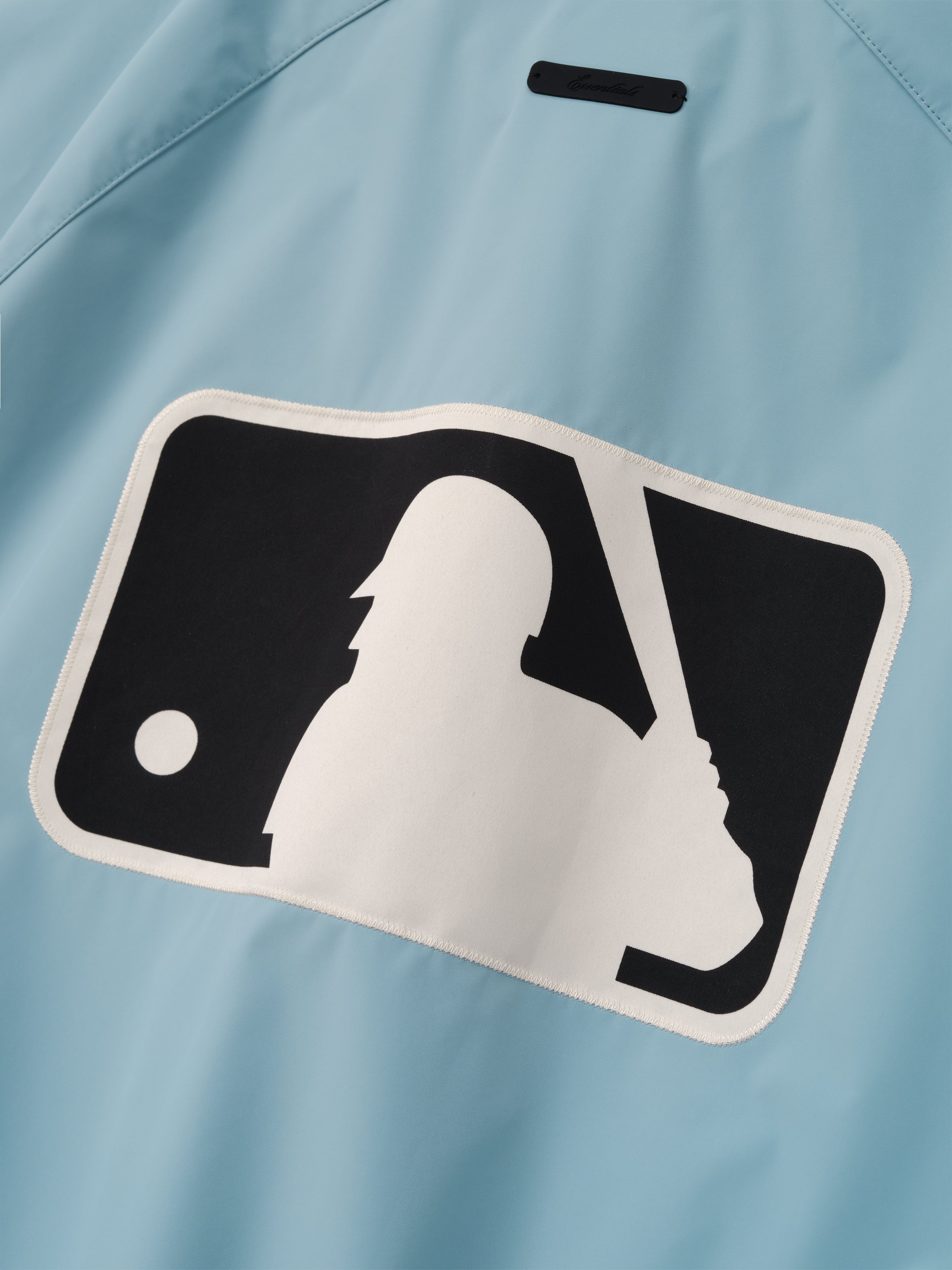 MLB Full Zip Bomber in pale blue featuring a large contrasting patch of a baseball player silhouette holding a bat, designed as stylish lightweight outerwear.