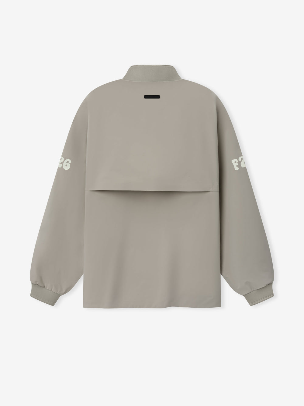 Half Zip Track Jacket in a soft muted taupe featuring long sleeves with white printed lettering on each arm, a high collar, and a unique layered back panel for modern outerwear style.