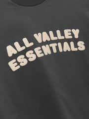 Kids Merch Tee in iron gray fabric featuring playful cream-colored bubble text "ALL VALLEY ESSENTIALS" across the front for a fun, casual kids' top.