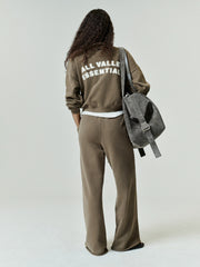 Womens French Terry Relaxed Half Zip in a muted olive tone, styled with relaxed fit pants and a casual backpack, showcasing a comfortable, minimalist streetwear look.