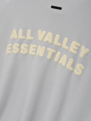Womens French Terry Relaxed Half Zip in a soft washed overcast grey fabric, featuring raised cream lettering “All Valley Essentials” across the chest for a casual streetwear top.