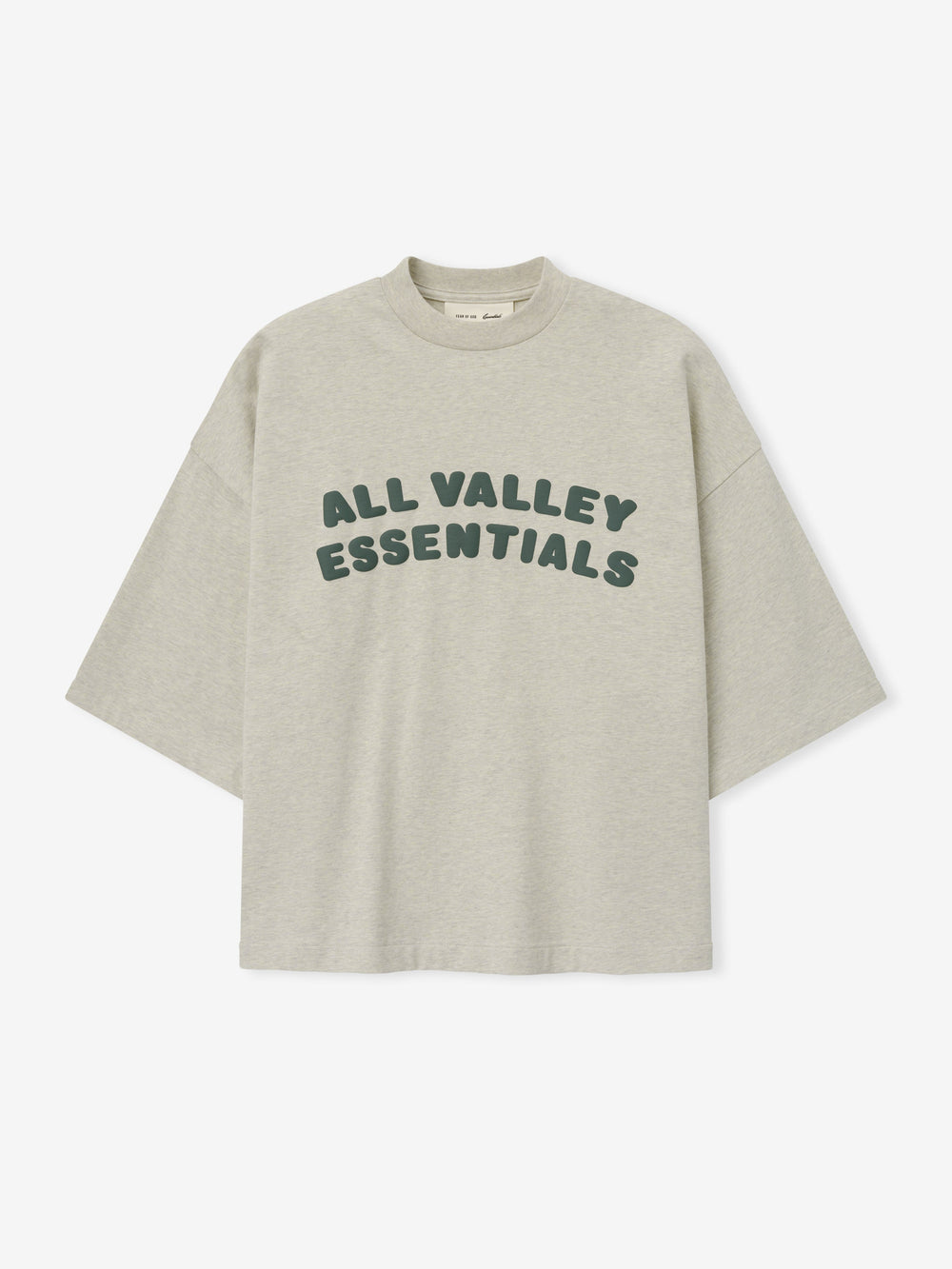 Merch Tee in soft vanilla heather featuring relaxed fit and oversized dark green "ALL VALLEY ESSENTIALS" lettering across the chest for a casual stylish top.